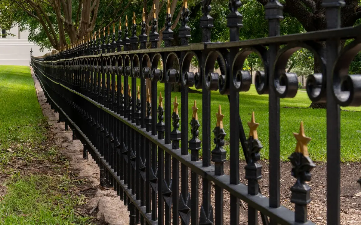 Black ornamental aluminum style fence with spear tops along a green lawn