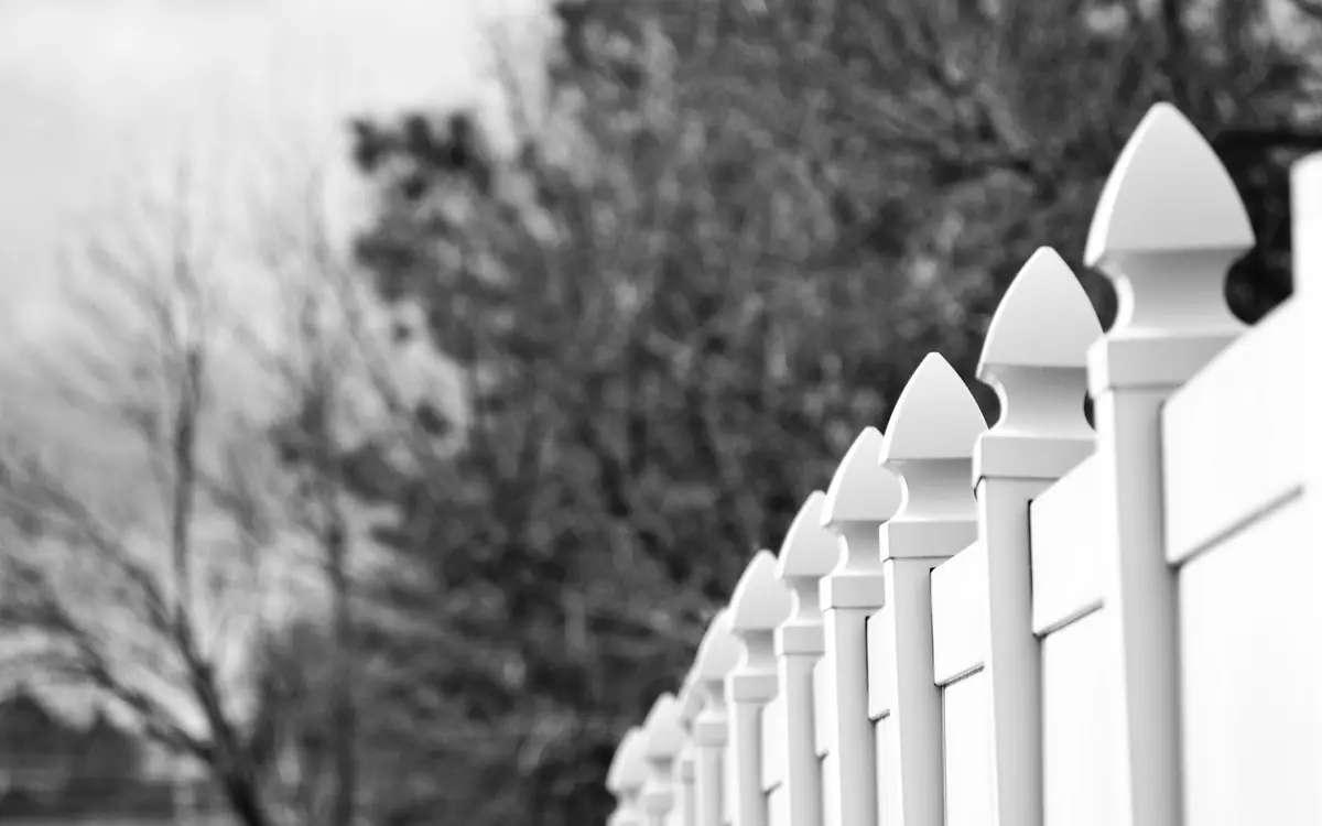 Row of white picket fence posts with pointed tops