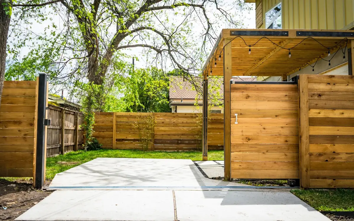 Horizontal cedar-tone wood privacy fence and matching gate beside a concrete driveway